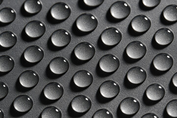 Detailed macro shot of repetitive uniform water droplets aligned in neat rows on a grey metallic surface