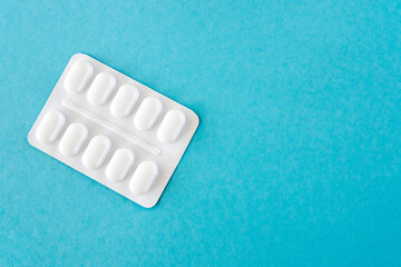 Tabletts in white package on the blue paper background.