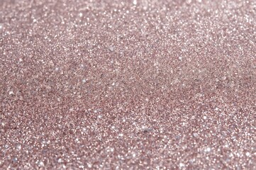 A full frame shot showcasing a dense layer of sparkling rose gold glitter with a shimmering effect
