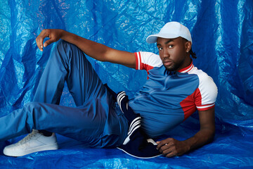 Stylish young man poses confidently against a vibrant blue backdrop showcasing modern fashion