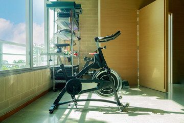 Indoor exercise bike in a bright home gym with fitness equipment and large windows