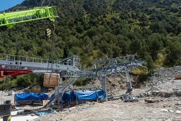Steel Aerial cableway station frame under assembly, crane lifting crate. Pylons with sheave...