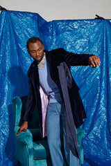 Striking young man poses confidently against a vibrant blue backdrop showcasing modern style