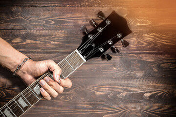 Music, sound. Musician hand holding a bass electric guitar neck isolated on a wooden vintage...