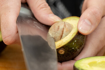 Close Up of Hands Cutting Fresh Avocado with Knife for Homemade Sushi Preparation