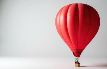 Obraz premium A red hot air balloon floats against a plain light gray background