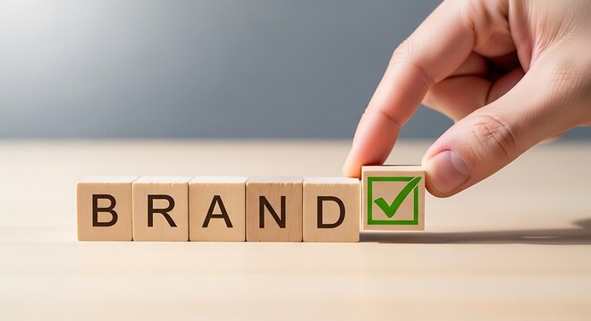 Hand placing checkmark on wooden blocks spelling brand to signify branding success and approval