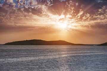 Stunning sunset with vibrant colors illuminating a tranquil ocean, clouds creating a dramatic...