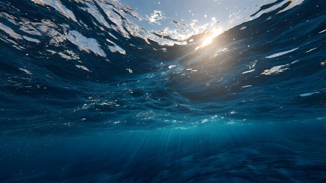 an underwater view of ocean waves with sunlight filtering through the surface.