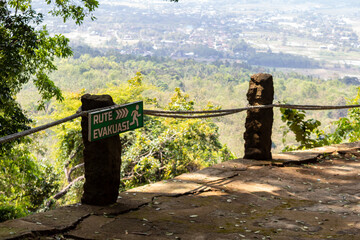 A view from a high-altitude viewpoint shows a weathered path with a green 
