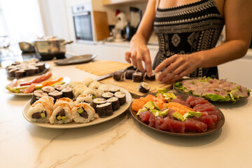 Woman Preparing Sushi Rolls with Fresh Ingredients on a Bright Kitchen Counter