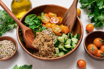 Gluten Free Quinoa Salad with Cucumber, Parsley, Mint and Yellow Cherry Tomatoes in Wooden Bowl on...