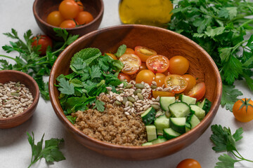Gluten Free Quinoa Salad with Cucumber, Parsley, Mint and Yellow Cherry Tomatoes in Wooden Bowl on...