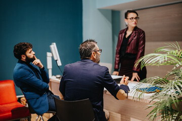 A group of business professionals gathered around a desk, discussing and collaborating in a modern...