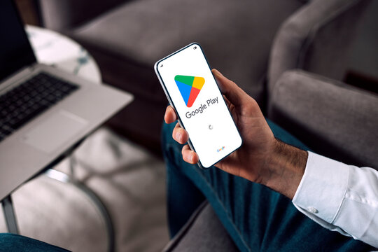 Google play on mobile phone screen. Man user holding a smartphone showing play store application launch screen.
