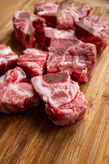 Raw, cut, fresh beef ox tail pieces used for soup broth or stews. Top down view, set on wooden...