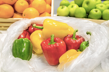 Fresh vegetables and fruits. Three sweet Red, Yellow, Green Peppers with oranges and green apple in wooden baskets at supermarket in the background.
