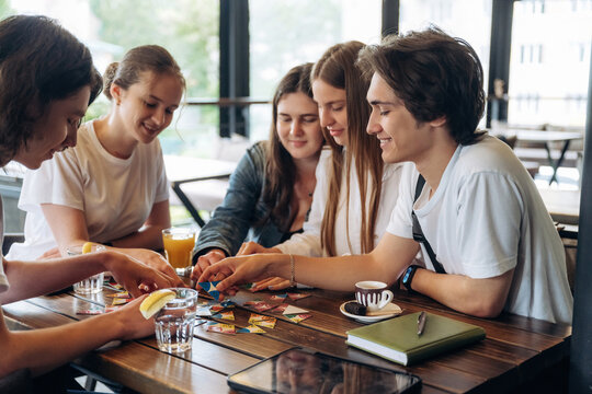 Having fun by playing the game by table. Group of young friends are in the cafe restaurant