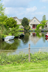 Typical beautiful Dutch landscape with some houses near the canal and a boat on the water. Typical summer day in the Dutch suburb with green trees and living area