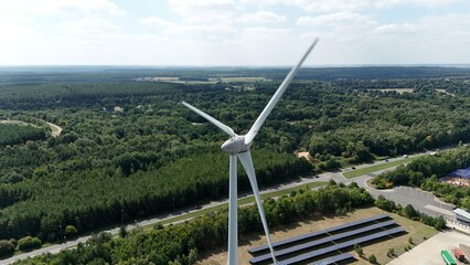 Aerial drone view of wind turbine energy generation electricity and verdant green rural forest...