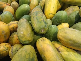A Vibrant Pile of Fresh Papayas, Green and Yellow, at a Local Market