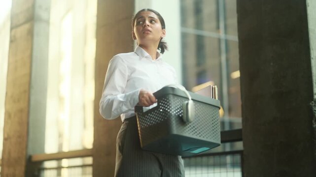 A sad indian business Woman get fired and leaving the office Holding a Container Inside a Modern Office Environment