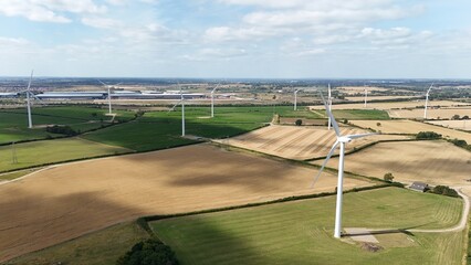 Aerial drone view of wind turbine power plants renewable energy electricity with rural English...