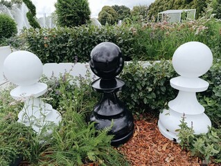 Giant chess pieces in garden surrounded by greenery and plants  