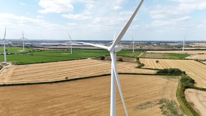 Aerial drone shot of wind turbines renewable power plant windmills generating electrical energy in England UK sunny day rural landscape.