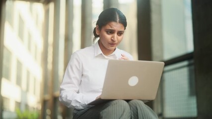A woman is showing a range of different emotions while she is working on her laptop in a modern office environment - Powered by Adobe