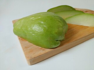 Sliced of baby chayote (labu siam) on wooden cutting board isolated on white background