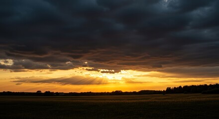 Scenic sunset over field with stormy sky and sun rays landscape