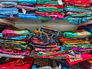 Neatly stacked colorful silk saris in racks in a textile shop, These exquisite, expensive sarees...