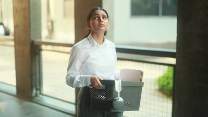 Portrait of fired sad young indian businesswoman carries her box with personal belongings leaving the office. - Powered by Adobe