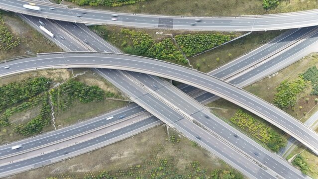 Aerial drone shot of busy motorway junction intersection with numerous bridges and lanes and vehicles near Rugby England UK M1 highway 