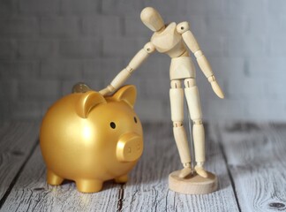 Wooden  mannequin stroking a piggy bank save keep money photo