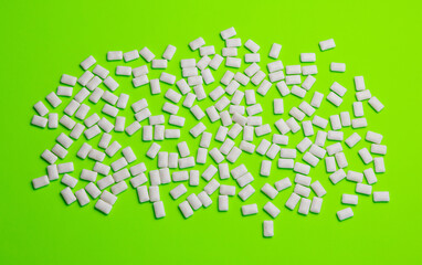 White mint gum scattered on green background, top view
