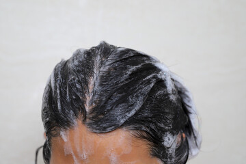A woman takes a shower and washes her hair in the bathroom at home.