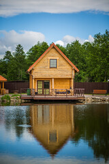 Obraz premium A small wooden house with a porch sits on a dock next to a body of water