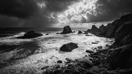 Monochrome seascape featuring rocks, waves, and stormy clouds above the water