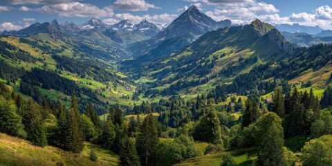 Obraz premium Alpine valley with snow-capped peaks. Lush green hills and forests