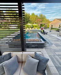Beautiful, luxury, modern backyard lounge area. Umbrella, sofa, lounge chairs table poolside. Hotel...