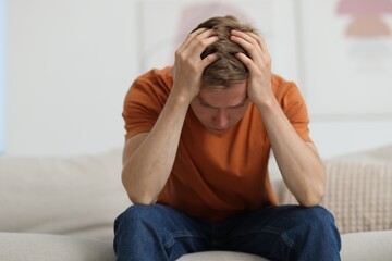 Sad man sitting on sofa at home