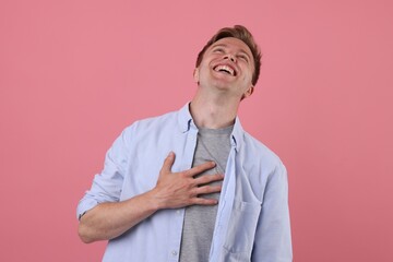 Handsome man laughing on pink background. Positive emotion
