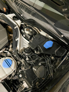 Gleaming engine parts under the hood reveal a mechanical symphony of gears, evoking Automaker's Day and Car Care Month