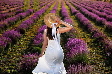Woman with straw hat in lavender field, back view