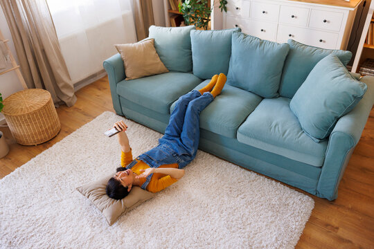 Woman having video call using smart phone while relaxing at home - Powered by Adobe
