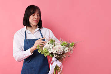 Florist with beautiful bouquet of flowers on pink background, space for text