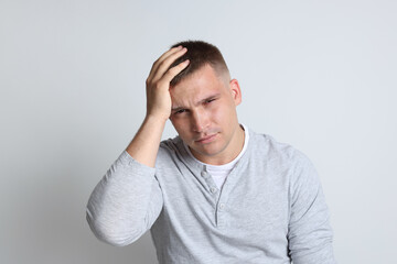 Man suffering from hangover on light grey background