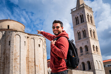 Hombre turista recorriendo la ciudad de Zadar, en Croacia, señalando sorprendido la antigua...